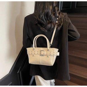Dettaglio della borsa tote in pelle crema con fibbie metalliche su scale urbane