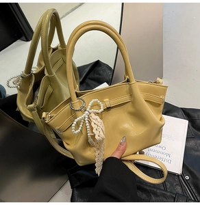 Detail einer hellgelben Leder-Beuteltasche mit Perlenbogen und Spitzenbesatz-Deko