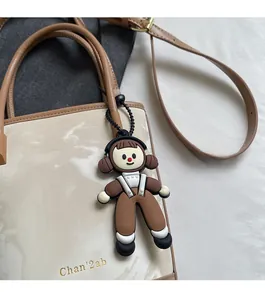 Détail d'une breloque de sac fille de dessin animé avec casque noir et chaîne