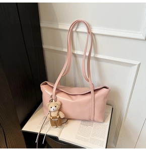 Detailed view of pink glossy leather hobo bag featuring a cute plush bear pendant
