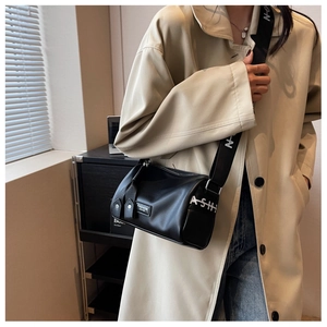 Détail du sac polochon en cuir noir avec large bandoulière ajustable à lettrage