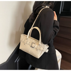 Dettaglio della borsa tote crema con occhielli in metallo e cinturino decorativo