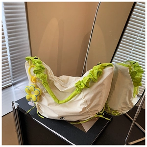 Détail du sac bandoulière en toile blanche avec bandoulière à volants verts et fleur