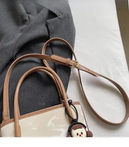 Détail du sac seau contrasté avec bandoulière réglable et breloque mignonne