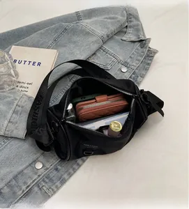 Close-up of the spacious interior of a black nylon crossbody bag with wide logo strap