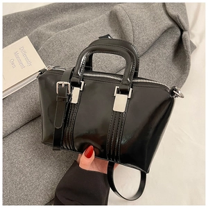 Detail of elegant black glossy patent leather handbag with silver metal hardware and top handles