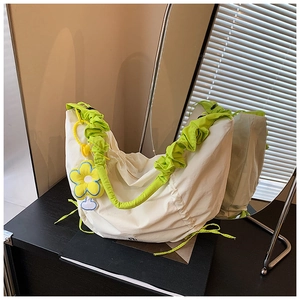 Détail du sac croissant blanc cassé avec bandoulière à volants verts et fleur