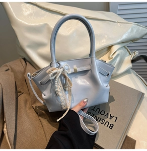 Nahaufnahme hellblaue Lederhandtasche mit Spitzen-Perlenschleife und Falten-Detail
