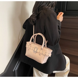 Dettaglio della borsa tote beige con rivetti metallici e tracolla indossata da una modella