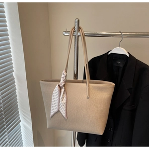 Detail of beige large tote bag in lychee grain texture with a decorative silk scarf