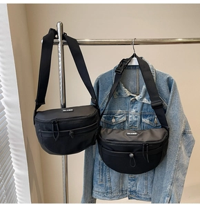 Détail de la sacoche noire avec poche en filet et bandoulière sur veste en jean