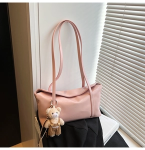 Detail shot of the pink baguette bag with a plush bear charm and metallic branding