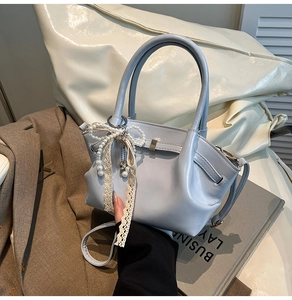 Detail der hellblauen Lederhandtasche mit Perlen-Spitzen Schleife auf einem Blazer