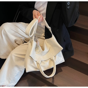 Detail of cream oil-wax leather tote with pearl charm on a vintage staircase