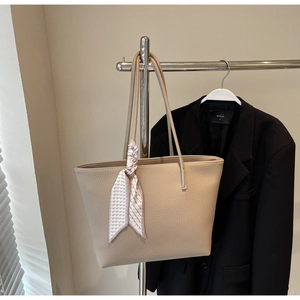 Close-up of beige lychee texture leather tote bag with a decorative heart print scarf