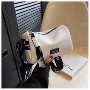 Détail du sac oreiller en cuir grainé blanc avec large bandoulière en toile noire élégante