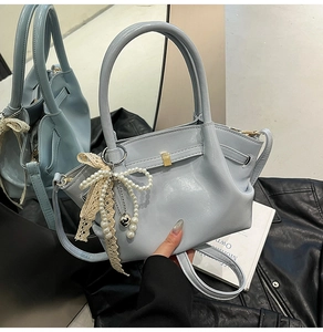 Detail der hellblauen Ledertasche mit Perlen-Schleifen-Anhänger und Gürtelschnalle