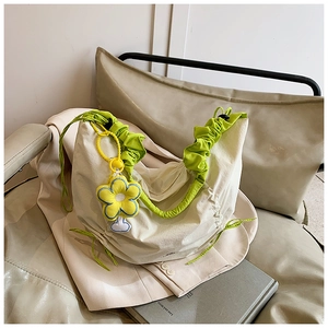 Détail du sac hobo avec poignée froncée verte et un accessoire fleur coloré