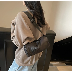 Detail of black nylon barrel crossbody bag with adjustable wide strap on model