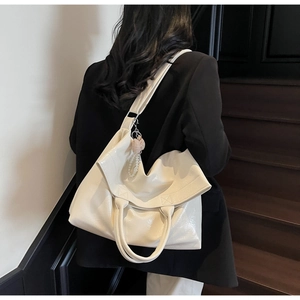 Detail of white glossy tote bag with pearl heart charm and strap on shoulder