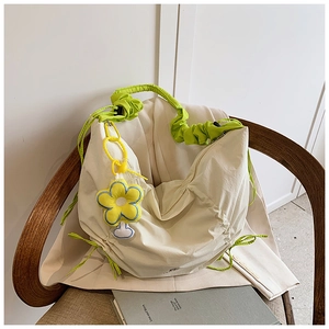 Détail du sac crème avec poignée froncée verte et breloque fleurie jaune