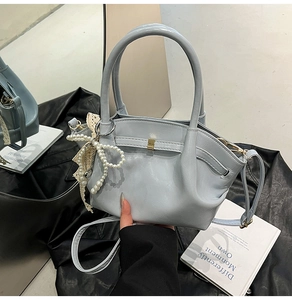 Detailansicht der hellblauen Handtasche mit Plissee-Design und Perlenanhänger
