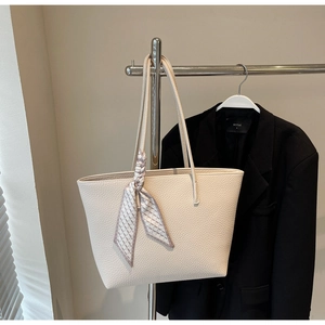Close-up of cream tote bag with lychee texture and plaid silk scarf on the handle