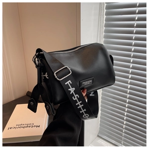 Détail du sac polochon en cuir noir grainé avec une large bandoulière logo tendance