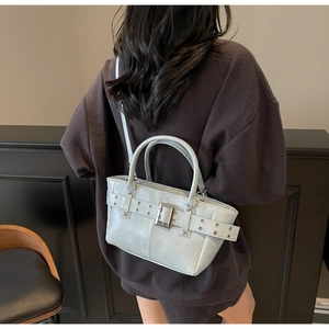 Dettaglio della borsa tote grigio-azzurra con fibbie metalliche indossata da una modella