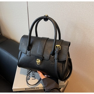 Details der schwarzen Lederhandtasche mit goldenem Drehverschluss und Business-Deko