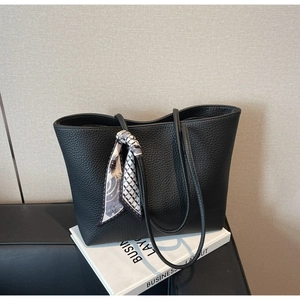 Close-up of black pebble leather tote bag with elegant geometric print silk scarf detail