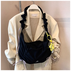 Détail du sac hobo noir plissé avec breloque fleur jaune et rubans violets élégants