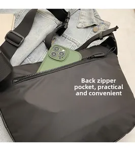 Détail de la poche zippée arrière d'un sac bandoulière en nylon avec un smartphone
