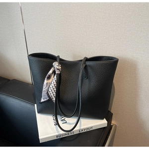 Close-up of black litchi pattern leather tote bag with a geometric printed scarf on handle