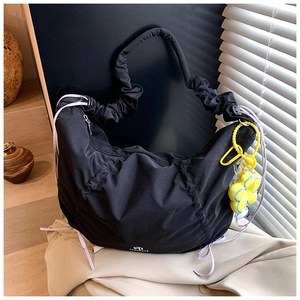 Détail du sac croissant noir avec tissu plissé et pendentif fleur jaune décoratif