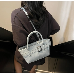 Modella che indossa la borsa tote azzurra con fibbia decorativa e borchie metalliche eleganti