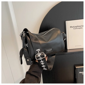 Gros plan sur la texture cuir grainé noir et la large bandoulière du sac à bandoulière