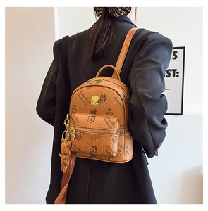 Detail of light brown leather backpack featuring Teddy Bear University graphic and charm