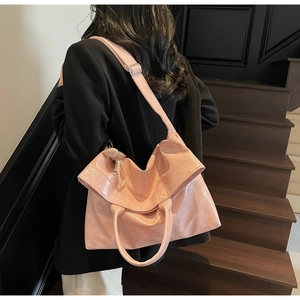 Pink faux oil wax leather tote bag shown on shoulder with pearl heart charm detail