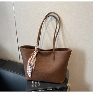 Close-up of brown litchi grain leather tote bag featuring a decorative geometric silk scarf
