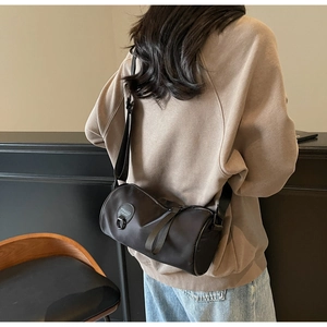 Adjustable wide fabric strap on a black nylon cylindrical crossbody bag for women
