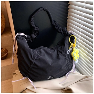 Détail du sac plissé noir avec cordon de serrage violet et pendentif fleur jaune vif
