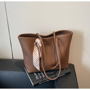 Detail of brown lychee leather tote bag with elegant checkered scarf accent