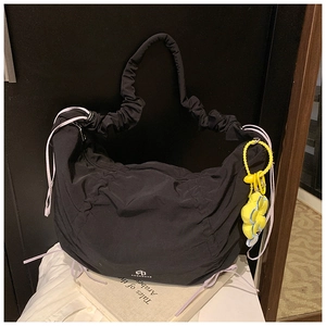 Détail du sac à bandoulière en nylon plissé noir avec cordon et pendentif fleur