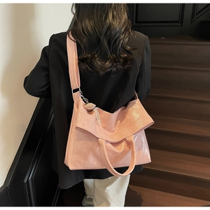 Detail of pink glossy tote bag with pleated texture and decorative pearl charm accessory