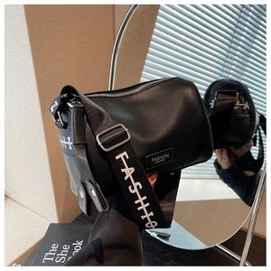 Détail du sac polochon noir en cuir avec une large bandoulière et lettrage blanc fashion