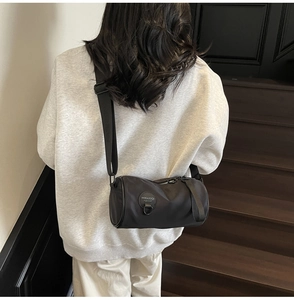 Close-up of a black nylon cylinder crossbody bag with an adjustable wide strap