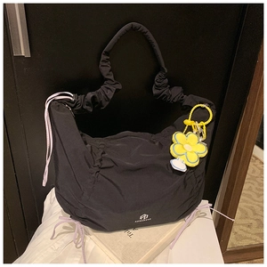 Détail du sac à bandoulière plissé en nylon noir avec cordon lilas et breloque fleur jaune