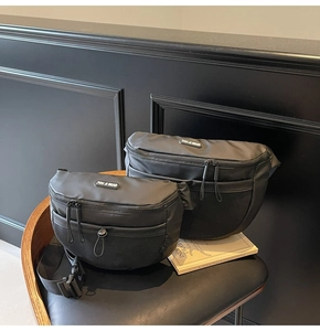 Détail de deux sacs bandoulière en nylon noir avec poches en filet et logo sur fauteuil en cuir