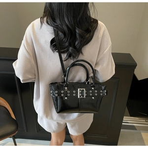 Dettaglio borsa tote nera lucida con occhielli metallici e cinturino con fibbia